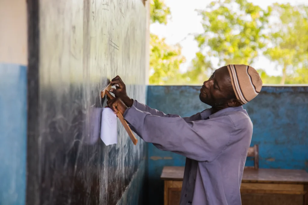 Ein Lehrer aus Sansibar schreibt etwas auf eine Tafel - wer Sansibar bereist, lernt auch viel über die lokale Kultur. Jetzt individuell beraten lassen - bei Ihrer Sansibar Expertin Katharina Fenners.