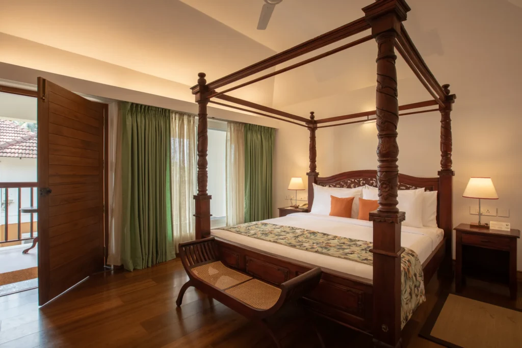 Ein Schlafzimmer mit Himmelbett und Balkon - die Einrichtung der Zimmer im Kalari Rasayana Gesundheitsresort ist ruhig, natürlich und klar. Buchbar ist der Aufenthalt bei Fenners Reisen.