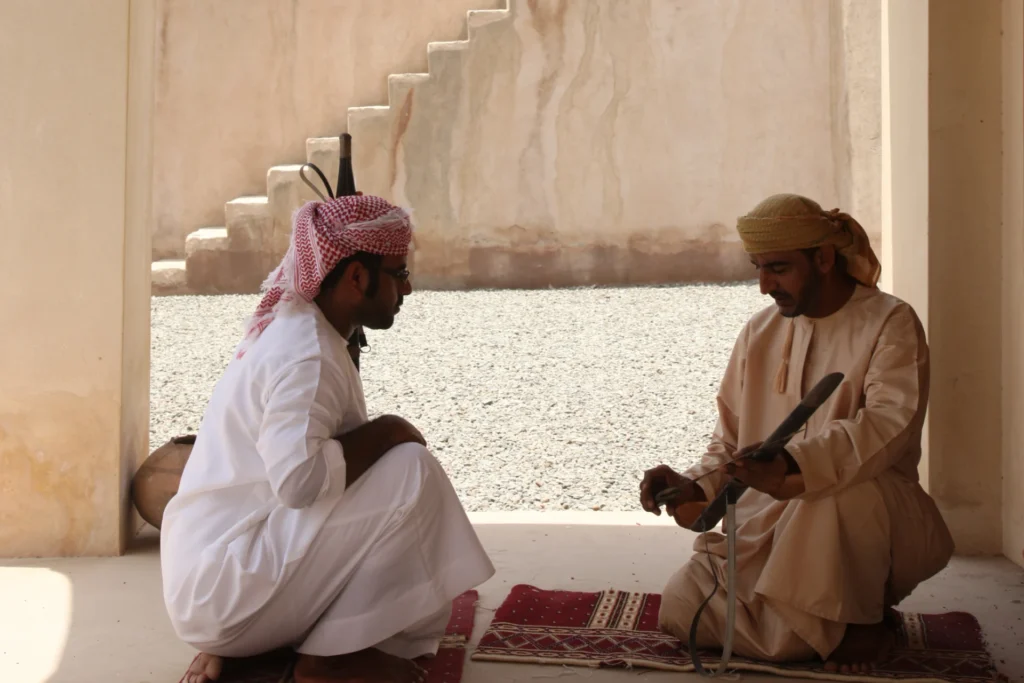Zwei Männer in traditioneller omanischer Kleidung präsentieren Handwerkskunft - auf einer Reise in den Oman verführt mit atemberaubenden Landschaften und eine faszinierenden Kultur. Buchbar bei Fenners Reisen!
