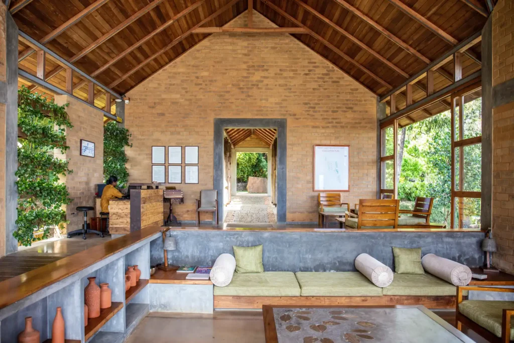 Hohe Decken und natürliche Materialien wie Stein und Holz prägen den Empfangsbereich dieser Gesundheitsklinik in Kerala, Indien - buchbar ist der ganzheitliche Wellnessaufenthalt bei Fenners Reisen!