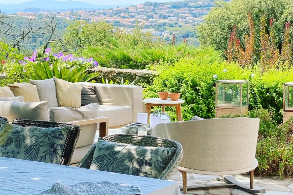 Sitzgruppe im Grünen, im Hintergrund der Blick auf ein mediterranes Dorf an der französischen Riviera - diese Luxusvilla mit Pool und Boullebahn kann exlusiv bei Fenners Reisen gebucht werden.