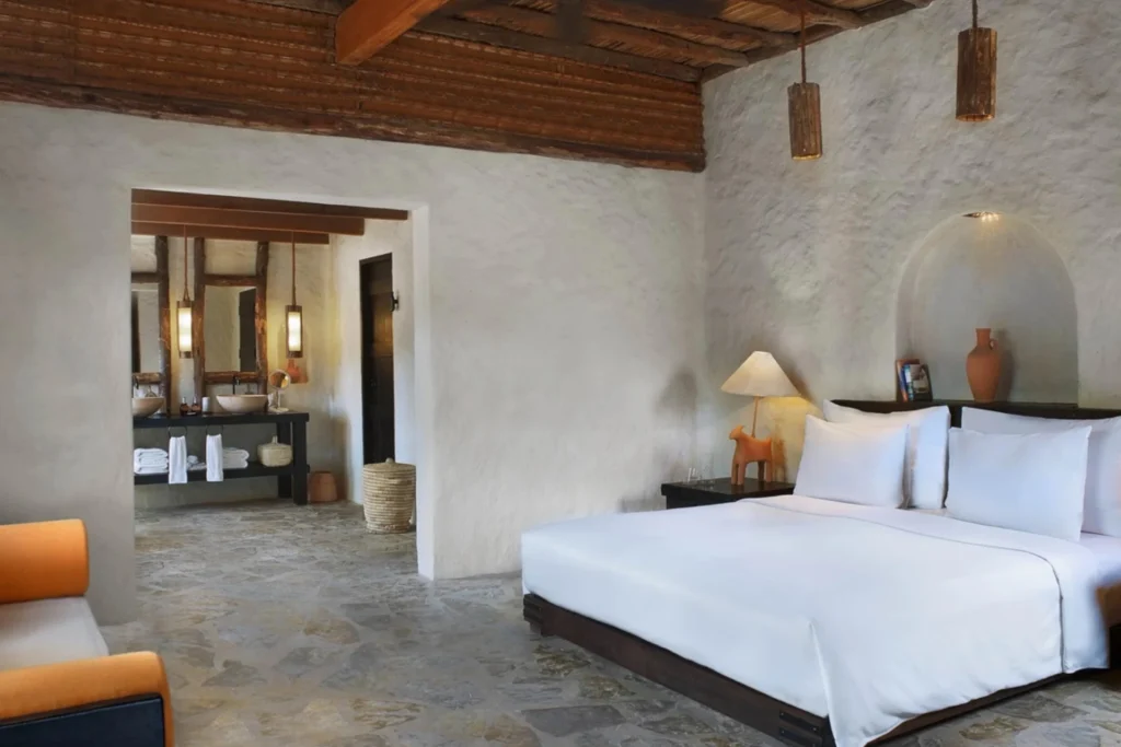 Schlafzimmer einer Pool Villa im Oman - hier dominiert ein natürliches Ambiente, geprägt von hohen Decken und authentischen Steinböden. Katharina Fenners kennt die besten Unterkünfte für Ihre Oman Reise und berät Sie individuell!