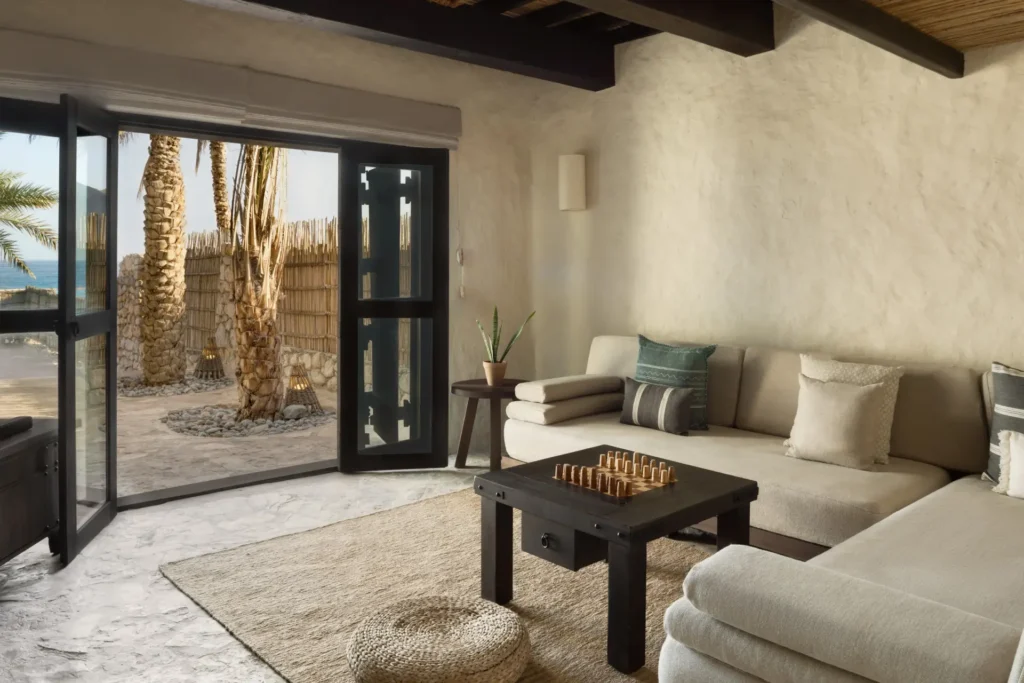 Helles, komfortables Sofa mit Blick auf Palmen und Strand - das Reiseland Oman besticht mit exklusiven Unterkünften. Katharina Fenners gestaltet Ihre luxuriöse Oman Reise individuell!