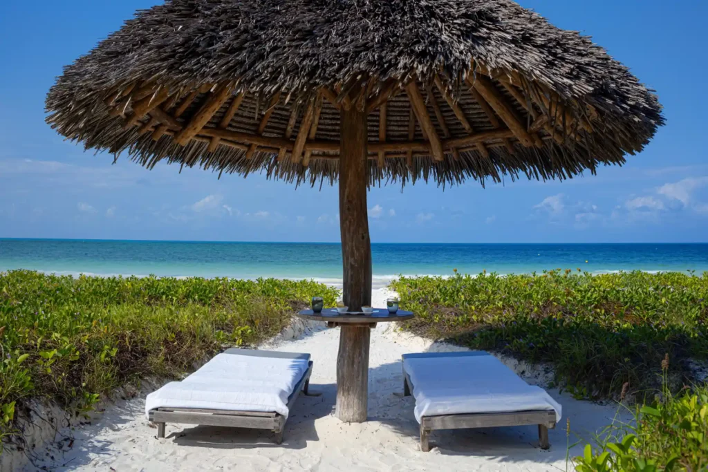 Zwei Liegen am einsamen Bilderbuchstrand vor einem Luxusresort auf Sansibar. Sie sind auf der Suche nach den besten Unterkünften für Ihren Urlaub auf Sansibar? Katharina Fenners berät Sie individuell!