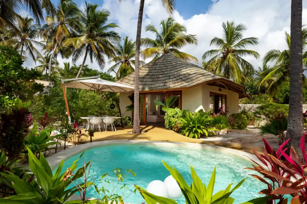 Palmen umsäumen den Wohnbereich und Pool einer Familienvilla dieses Luxusresorts auf Sansibar, buchbar bei Fenners Reisen