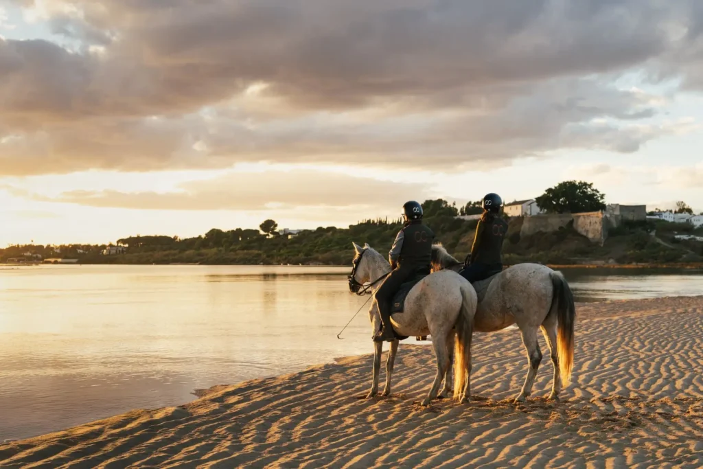 Zwei Reiter an einem einsamen Sandstrand im Abendlicht - ein Portugal Luxusurlaub verwöhnt mit zahlreichen unvergesslichen Momenten - buchen Sie Ihren individuellen Portugal Urlaub bei Fenners Reisen!