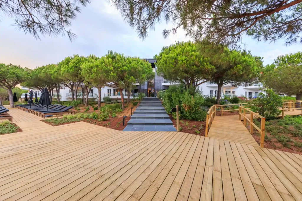 Blick von vorn auf das von Pinien umrahmte Boutiquehotel Octant Praia Verde. Das fußläufig vom gleichnamigen Strand entfernte Hotel kann bei Fenners Reisen individuell gebucht werden, zum Beispiel für einen Portugal Familienurlaub oder romantische Tage zu zweit.