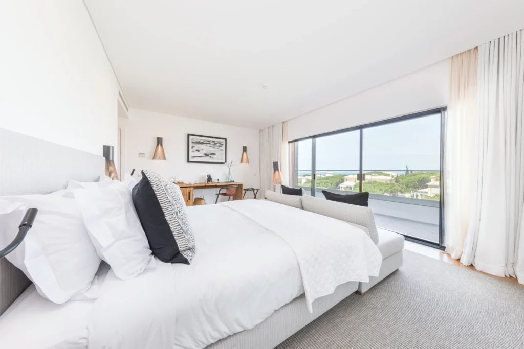 Das helle Deluxe-Zimmer mit Meerblick mit Blick über Pinienwald und Meer zählt zu den hochwertigsten Zimmerkategorien des Octant Praia Verde und kann bei Fenners Reisen gebucht werden.