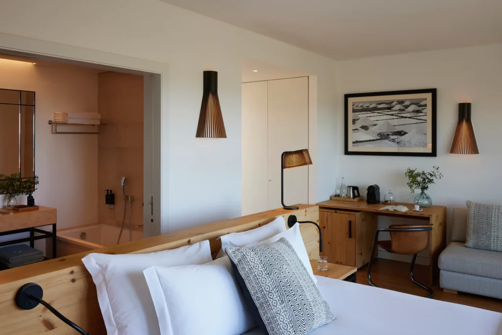 Dieses Superior-Zimmer mit Meerblick zeichnet sich durch viel Holz aus, große Schiebetüren lassen Licht ins Badezimmer und machen den Blick frei auf Pinien und Meer. Individuell buchbar für Ihren Urlaub an der Algarve bei Fenners Reisen!