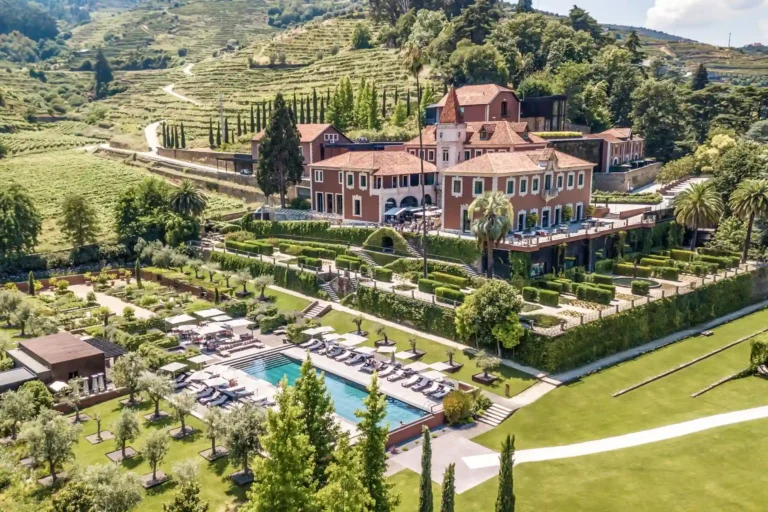 Blick auf das von malerischer Hügellandschaft umgebene Anwesen und den Hauptpool des Six Senses Douro Valley, buchbar für einen individuellen Portugal Luxusurlaub bei Fenners Reisen.