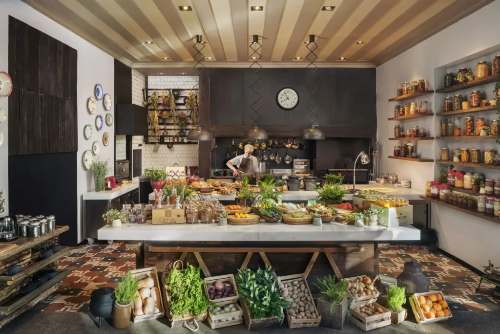 Obst, Gemüse und Kräuter aus dem eigenen Garten liegen im Six Senses Douro Valley auf der Theke, im Hintergrund kreiert ein Koch frische Gerichte. Buchen Sie jetzt Ihren Luxusurlaub in Portugal bei Fenners Reisen!
