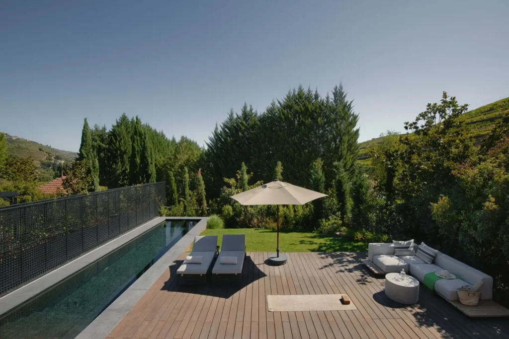 Blick auf den langen Privatpool und die große, möblierte Terrasse einer Pool-Villa mit einem Schlafzimmer im reizvollen Douro Valley in Portugal. Die Villa liegt nur eine Stunde vom Flughafen Porto entfernt und ist individuell bei Fenners Reisen buchbar.