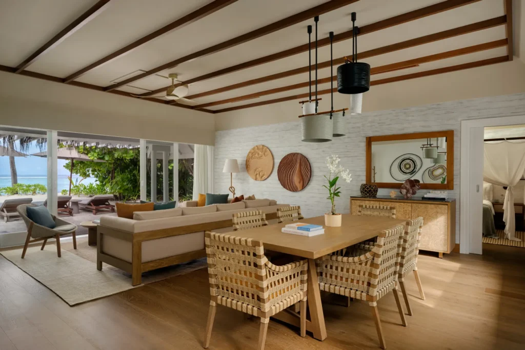 Wohnbereich einer stilvollen Strandvilla-Suite mit drei Schlafzimmern, die Platz für bis zu sechs Erwachsene und drei Kinder bietet. Buchbar für einen Luxus-Familienurlaub auf den Malediven bei Fenners Reisen!