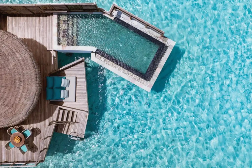 Blick aus der Luft auf eine Wasservilla mit Pool des Six Senses Kanuhura, umrahmt vom türkis glitzernden Meer. Ein Highlight für Ihre Luxusreise auf die Malediven, individuell buchbar bei Fenners Reisen!