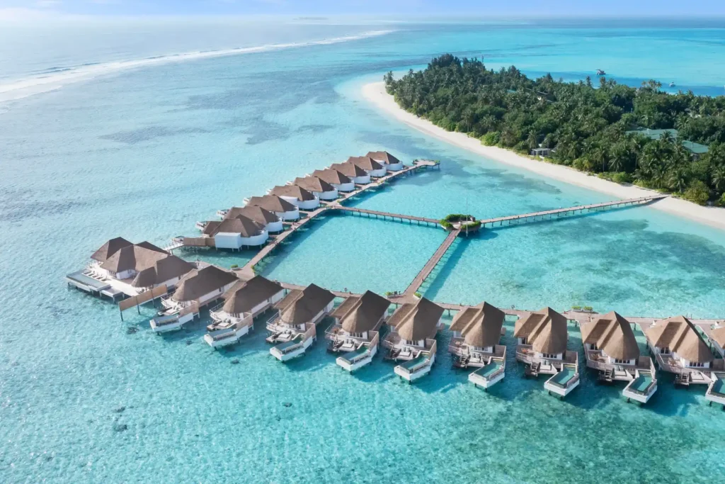 Vogelperspektive auf die Wasservillen des Six Senses Kanuhura auf den Malediven, die sich wie eine Perlenschnur durch den türkisen Ozean ziehen. Buchbar für Ihre Luxusreise auf die Malediven bei Fenners Reisen!