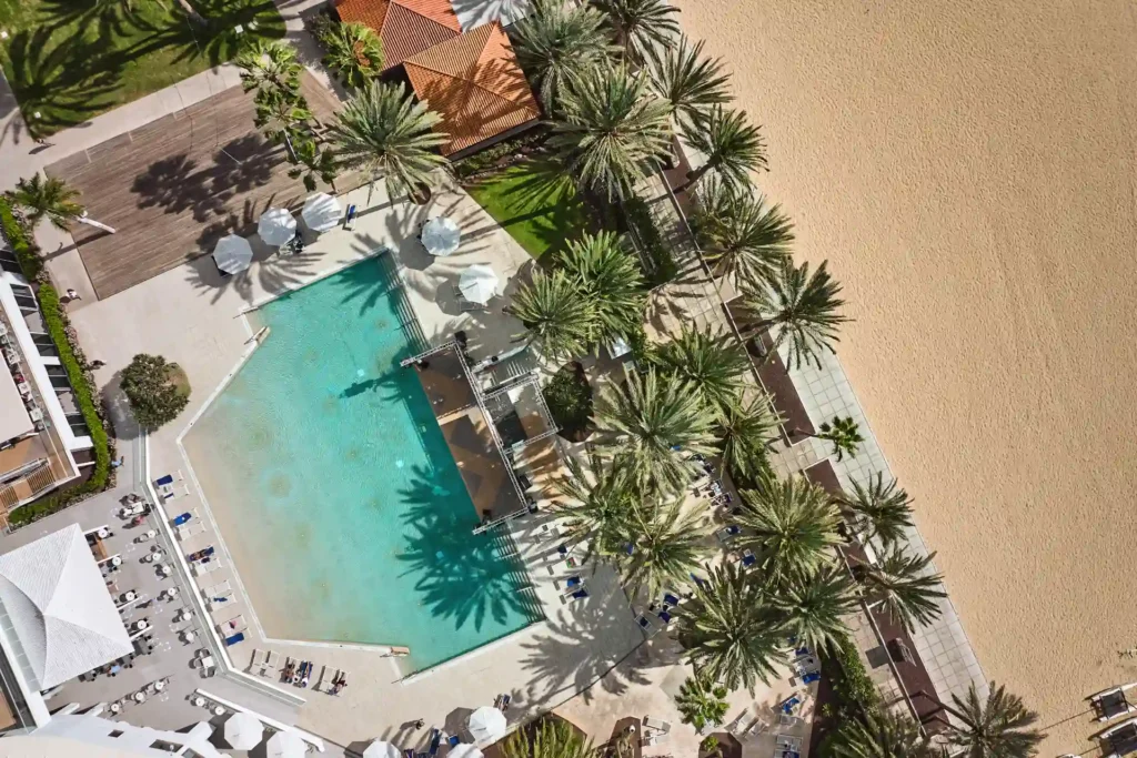 Blick aus der Luft auf den Hauptpool direkt am Strand des ROBINSON Jandia Playa, buchbar für einen entspannten Fuerteventura Cluburlaub bei Fenners Reisen