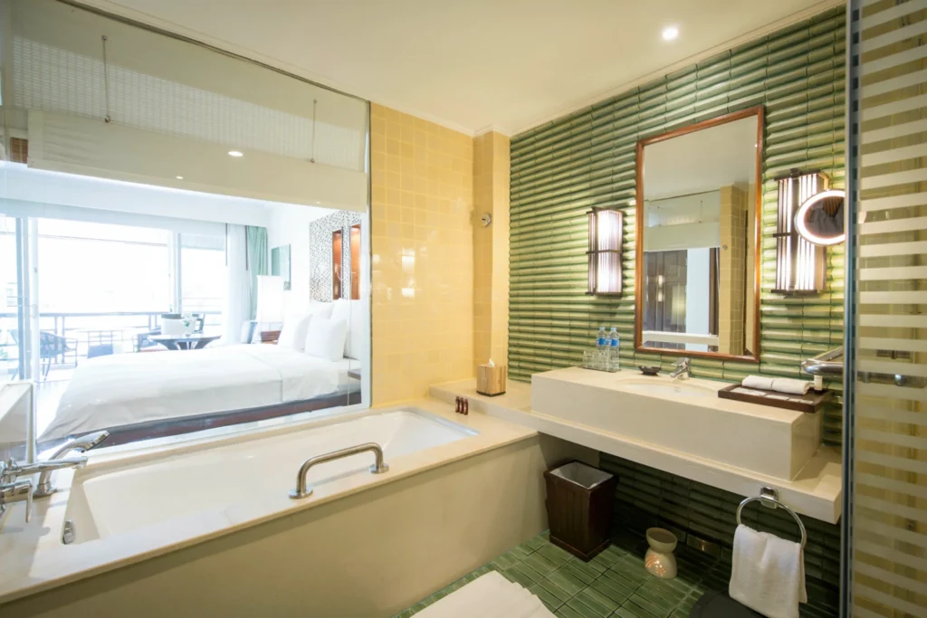 Das Badezimmer eines Klassik-Doppelzimmers bietet durch eine große Glasscheibe viel Licht und freien Blick bis hinaus ins Grüne - individuell buchbar für Ihren Thailand Cluburlaub bei Fenners Reisen!