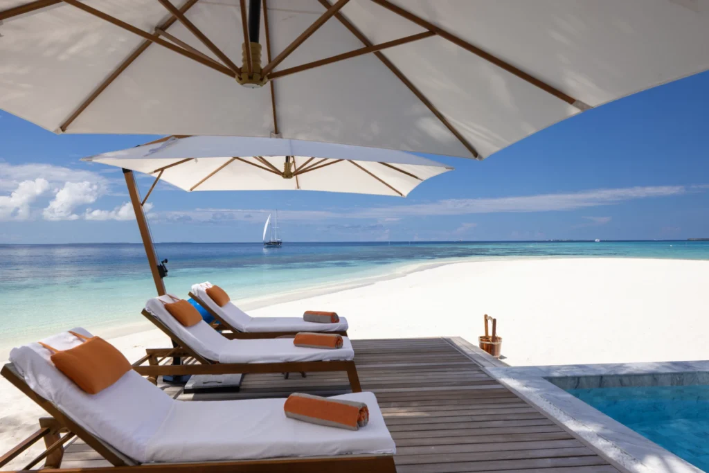 Liegen am Pool des V Villas Maldives at Mirihi, im Hintergrund der strahlend weiße Sand. Jetzt bei Fenners Reisen buchen!