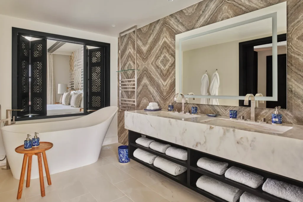 Eine freistehende Wanne und ein riesiges Doppelwaschbecken aus Naturstein prägen diese Badezimmer einer Residenz mit zwei Schlafzimmern des Viceroy at Ombria Algarve, die individuell bei Fenners Reisen gebucht werden kann.