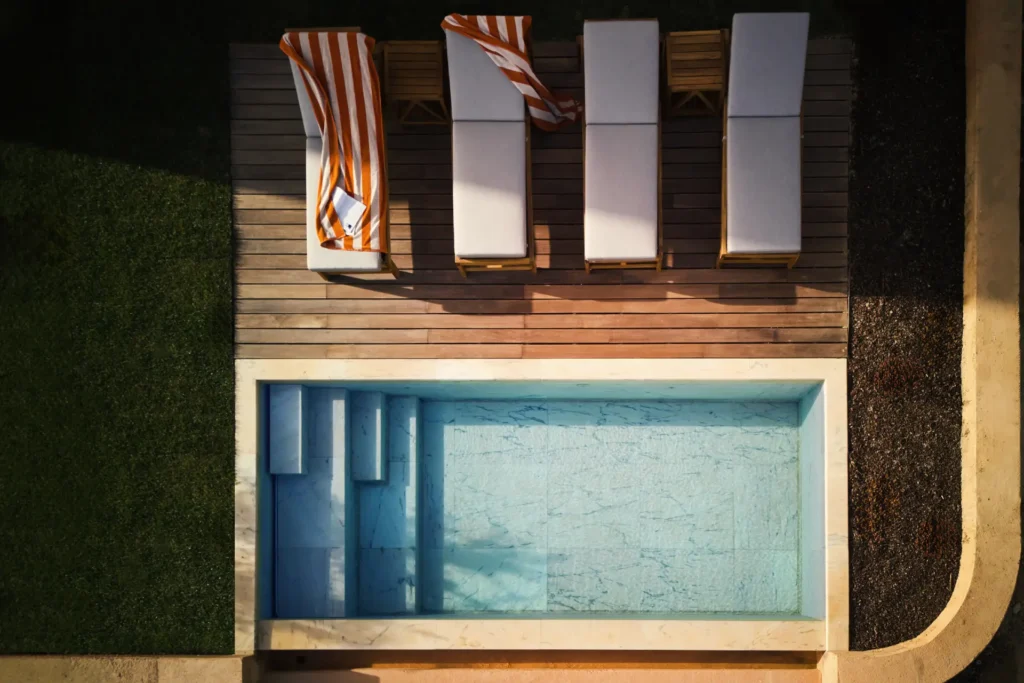 Pool einer Residenz mit zwei Schlafzimmern mit vier Liegen und bunt gestreiftem Handtuch - individuell buchbar für Ihren Aufenthalt im Viceory at Ombria Algarve bei Fenners Reisen.