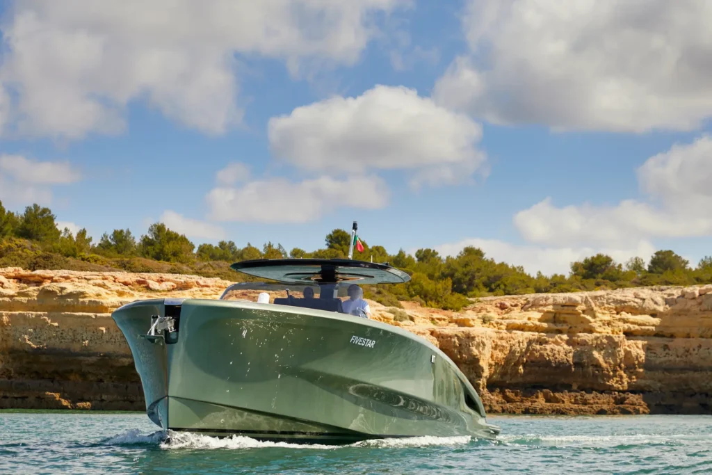 Die Yacht des Vila Vita Parc vor dem Hintergrund der ikonischen Algarve-Felsen über dem Sandstrand des Hotels. Die Yacht steht für individuelle Exkursionen bereit - ein Highlight des Aufenthalts in diesem Luxusresort, der ganz einfach bei Fenners Reisen gebucht werden kann!