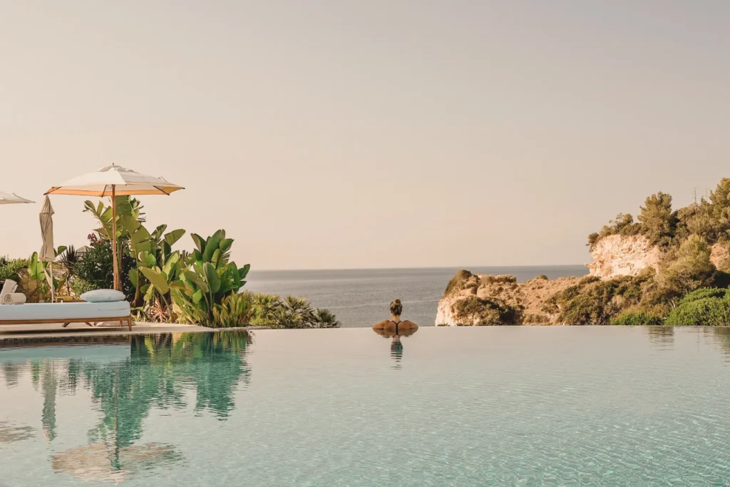 Eine Frau genießt den unendlich weiten Blick übers Meer aus einem Infinity Pool des luxuriösen Vila Vita Parc Hotels in Portugal. Der Aufenthalt kann individuell bei Fenners Reisen gebucht werden.
