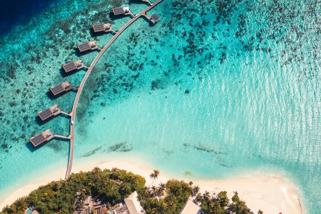 Vogelperspektive auf die Wasservillen und den strahlend weißen Strand des Park Hyatt Maldives Hadahaa. Katharina Fenners gestaltet Ihren Urlaub in diesem abgelegenen Paradies.