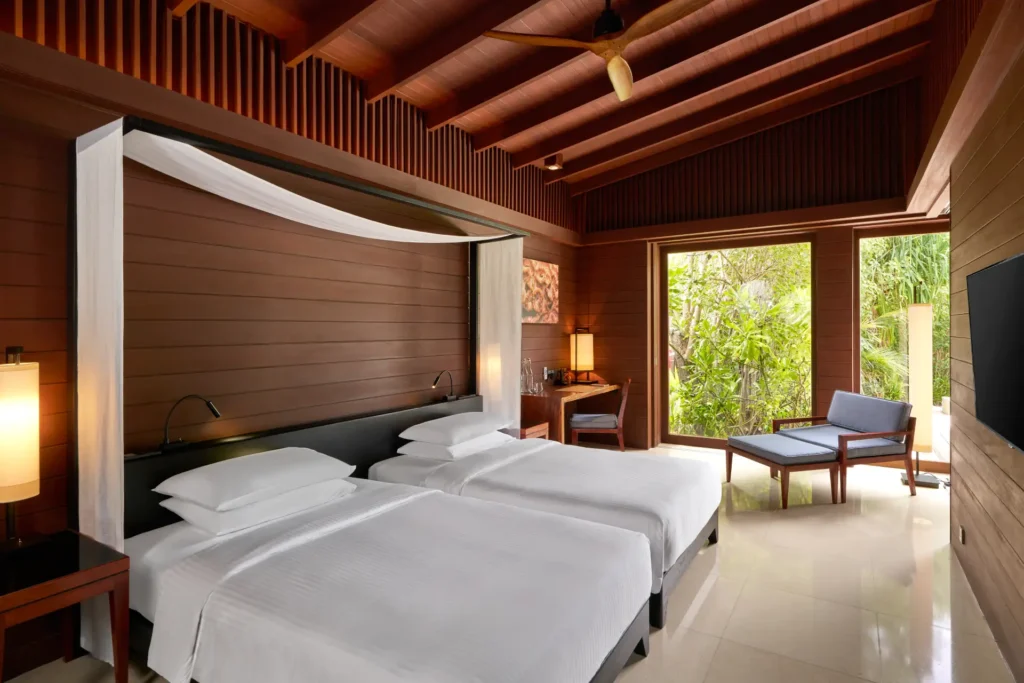 Twin-Betten mit Blick ins Grüne in einer Strand-Villa mit Pool und zwei Schlafzimmern des Park Hyatt Maldives Hadahaa. Die Villa eignet sich für bis zu vier Erwachsene und zwei Kinder und kann individuell bei Fenners Reisen gebucht werden.