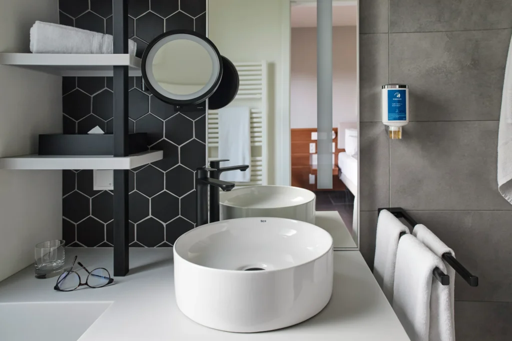 Moderne, doch schlichte Akzente prägen das Badezimmer des Klassik Doppelzimmers mit Golfplatzblick im ROBINSON Quinta da Ria, individuell buchbar für einen aktiven Urlaub an der Algarve bei Fenners Reisen.