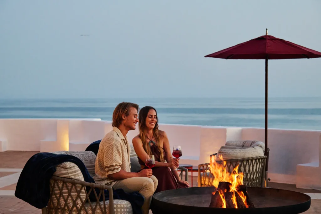 Paar genießt die Feuerstelle am Meer - eine von zahlreichen Annehmlichkeiten der Villa Red Chalet an der Algarve. Buchen Sie die Villa bei der Portugal-Expertin Katharina Fenners!