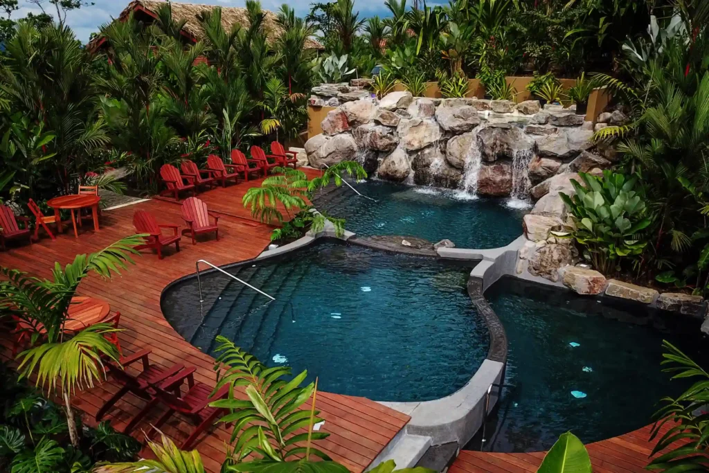 Blick auf den mineralischen Pool mit Wasserfall des vom Dschnungel umschlossenen Boutiquehotels Amor Arenal in Costa Rica. Buchen Sie eine individuelle Costa Rica Rundreise bei Fenners Reisen!