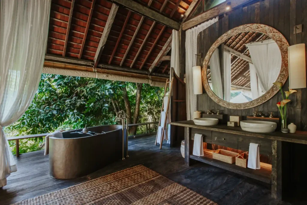 Dieses Badezimmer einer Regenwald-Bale mit Pool bietet eine freistehende Wanne und weite Blicke über die tropische Natur. Jetzt bei Fenners Reisen buchen!