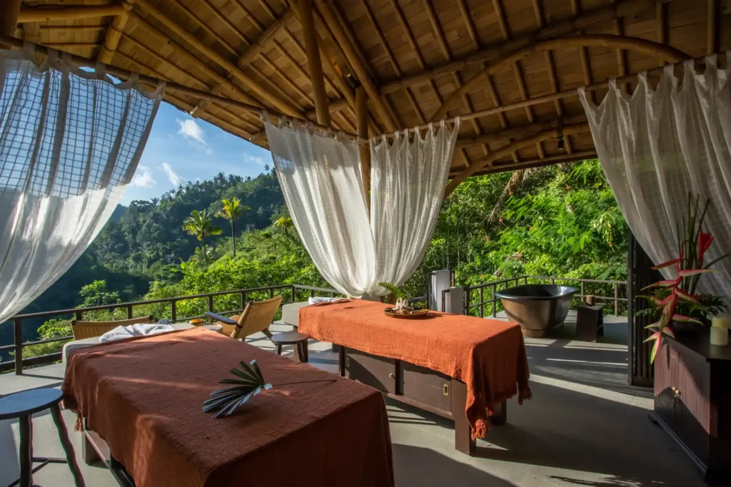 Die Spa-Liegen im offenen Spa-Bale des Buahan, A Banyan Tree Escape bieten weite Blicke über Reisfelder und Regenwald. Jetzt Ihren Bali Luxusurlaub bei Fenners Reisen buchen!