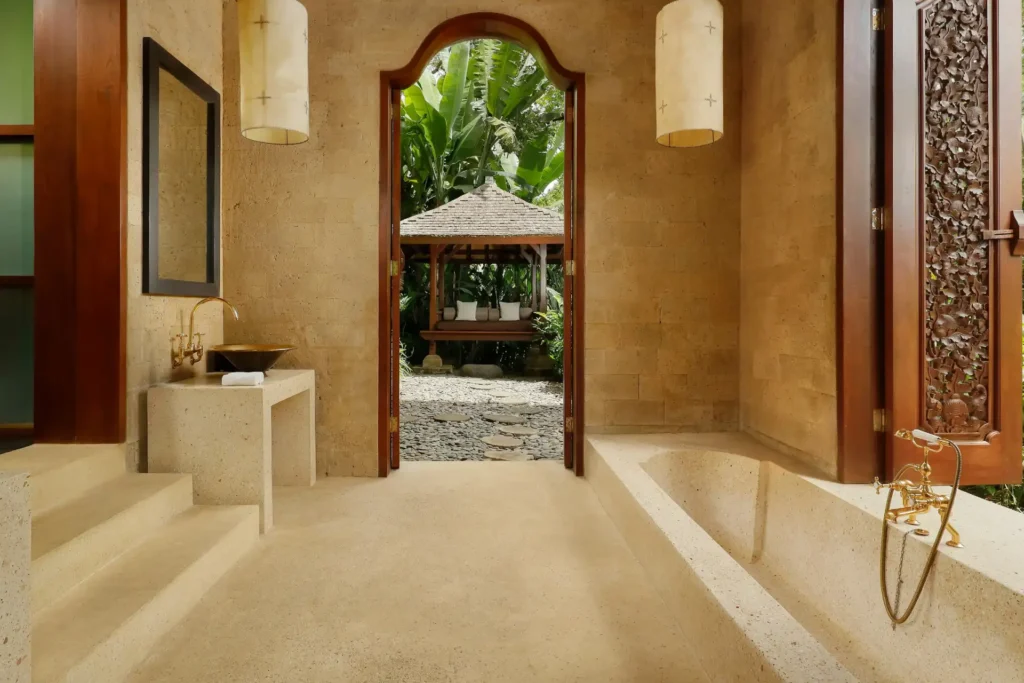 Sandfarbener Stein und klare Linien prägen das edle Bad einer Terrace Suite in der Tirta Ening Residenz in Bali, die bei Fenners Reisen gebucht werden kann