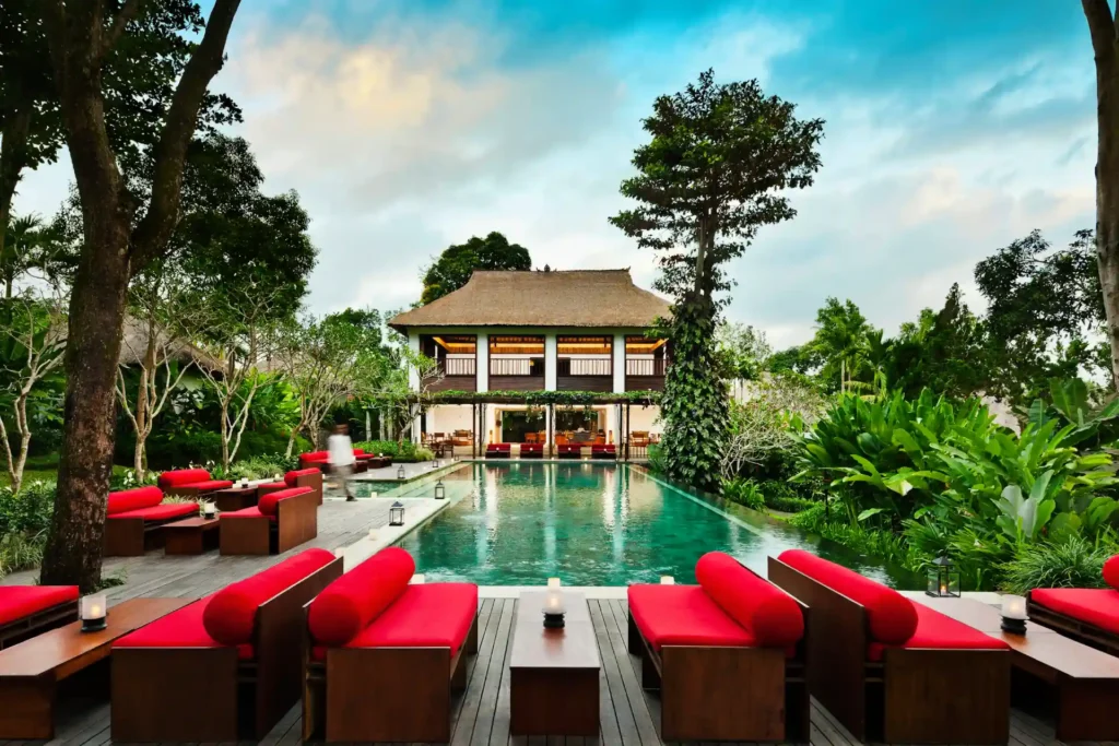 Rote Lounge-Sofas umrahmen den Hauptpool des luxuriösen COMO Uma Ubud Hotels auf Bali. Sie planen eine Bali Rundreise? Katharina Fenners kennt die besten Resorts und gestaltet Ihren Aufenthalt individuell!