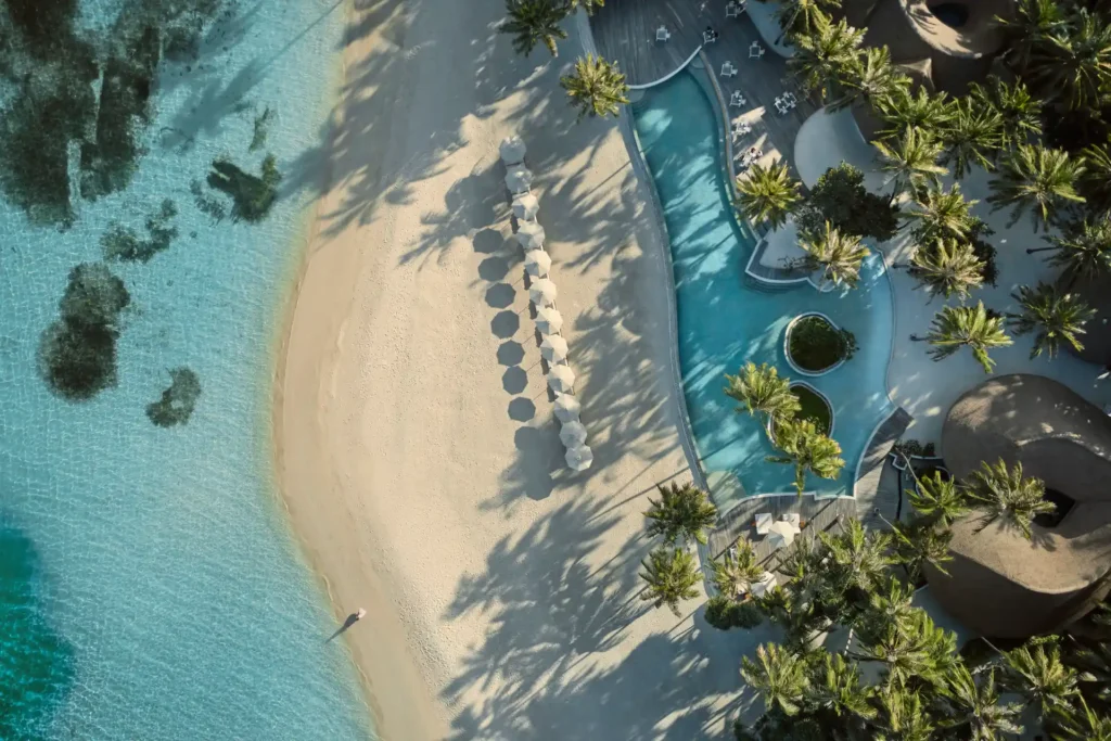 Vogelperspektive auf das COMO Maalifushi - hier treffen türkises Meer, weißer Traumstrand, exklusiver Pool und tropische Natur aufeinander. Buchbar bei der Malediven-Expertin Katharina Fenners.