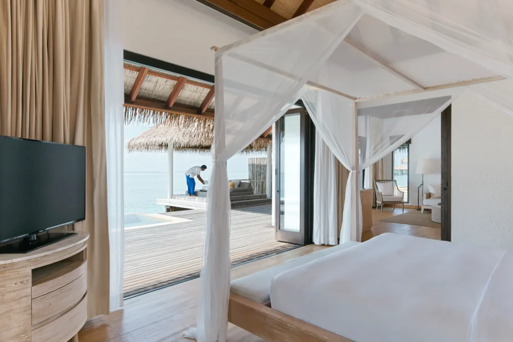 Das Schlafzimmer dieser Wasser-Villa des COMO Maalifushi öffnet sich zum privaten Pool und dem türkis glitzernden Meer - buchbar bei Fenners Reisen